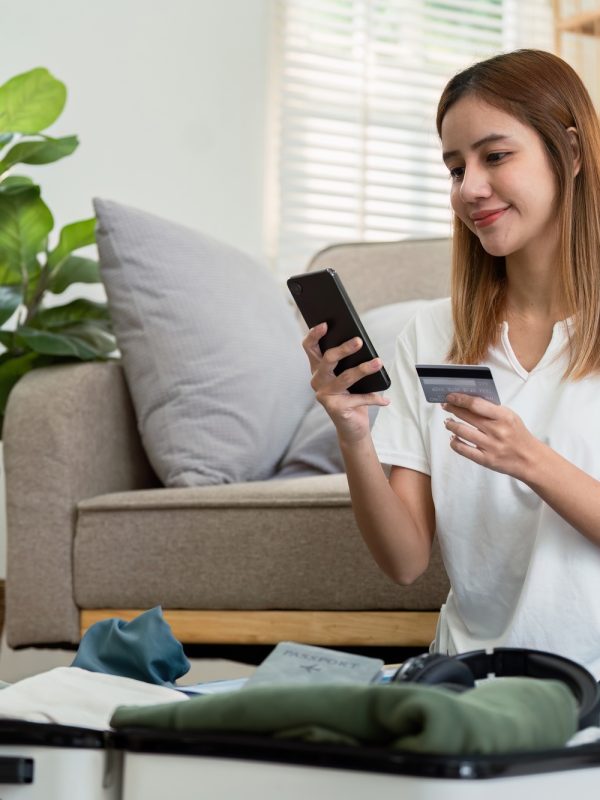 Happy young woman with credit card booking vacation at travel agency or making hotel reservation Happy young woman with credit card booking vacation at travel agency or making hotel reservation